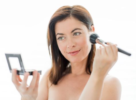 portrait of a beautiful mature lady using professional brushes to apply powder on her cheekbones