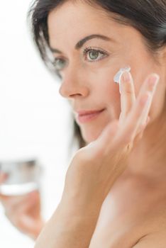 portrait of a beautiful mature lady preventing wrinkles by using luxurious face lotion
