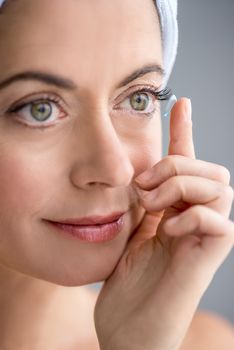close up of an attractive mature lady putting on contact lenses in her green eyes