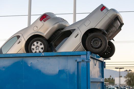 2 junk cars in a dumpster