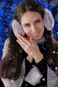 Beautiful girl holding a small gift box with snow falling around her.