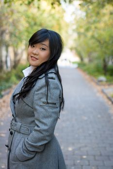 Portrait of beautiful young girl standing on a walk way bonded by trees looking hopeful