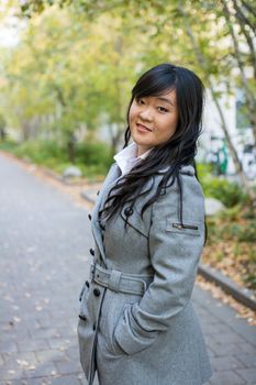 Portrait of beautiful young girl standing on a walk way bonded by trees looking hopeful