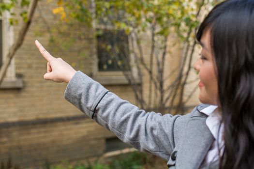 Portrait of young attractive girl pointing at something on the trees at the side of a road