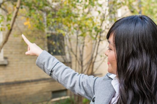 Portrait of young attractive girl pointing at something on the trees at the side of a road