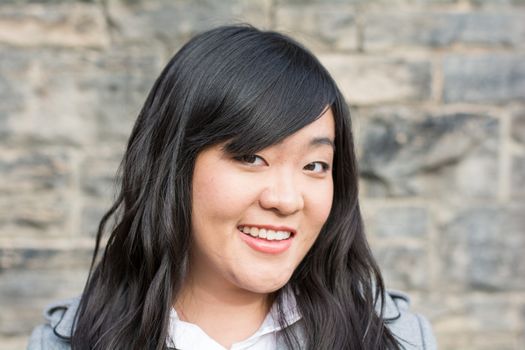 Portrait of attractive young girl in front of a wall with a weird smirk on her face