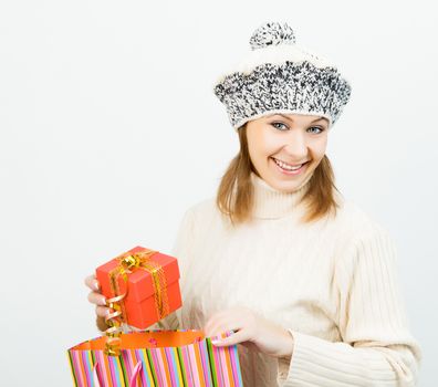 Charming smiling girl in winter cap holding a gift box