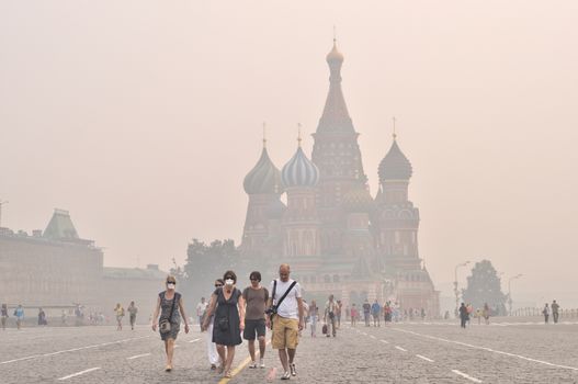 Smog in Moscow, August 2010, tourists in gas mask on Red Square against St. Basil's Cathedral