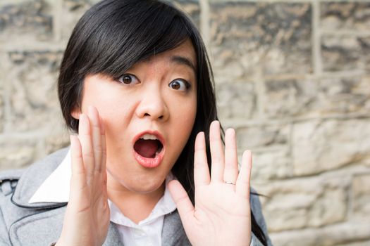 Portrait of attractive young woman looking surprised and screaming out loud