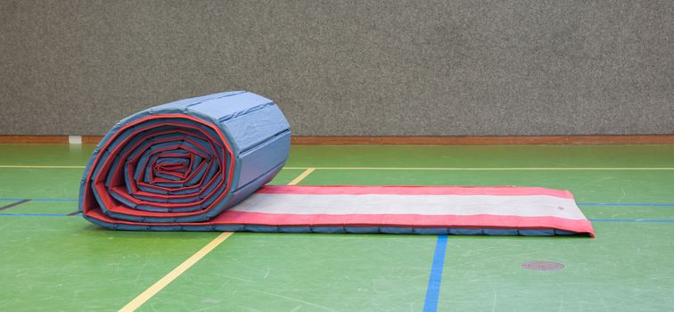 Very old long mat on a green court, school gym