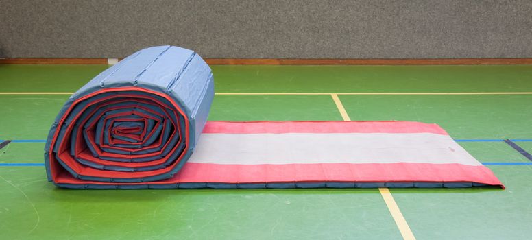 Very old long mat on a green court, school gym