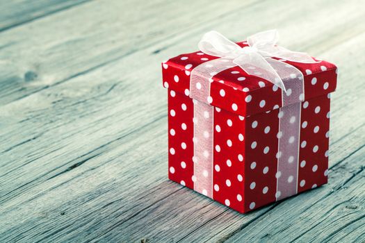 red gift box with  bow on wood background