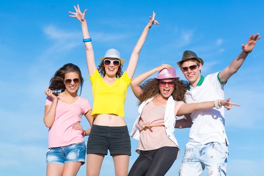 Group of young people having fun on a blue summer sky