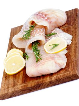 Two Slices of Raw Cod Fish Fillet with Lemon and Rosemary on Wooden Cutting Board isolated on white background