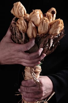 dirty and old hands taking a bouquet of dried roses