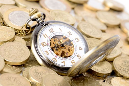 Concept of time is money, old watch on a pile of coins