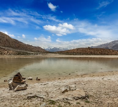 Mountain trekking concept background - trekking hiking boots at mountain lake in Himalayas