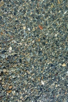 colorful pebbles at the waters edge in clear sea water early morning light. perfect texture or background