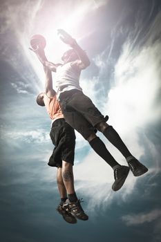 Two Basketball players playing street basket and jumping together to catch the ball
