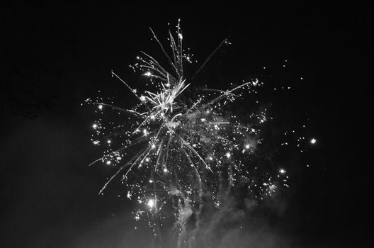 Black and white image of a firework exploding in the night sky.