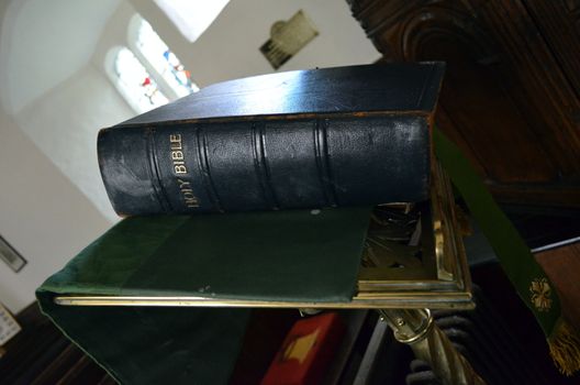 An old Holy Bible on a church pulpit ready for the reading of the Sermon by the Preacher.