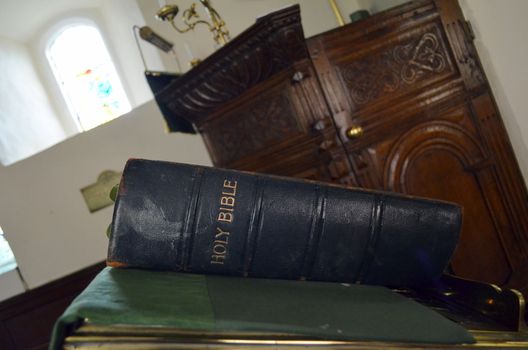 A Holy Bible on a pulpit waiting to be opened and read to the congregation. Image taken at St Peters church in Twineham,Sussex,England in November 2013.