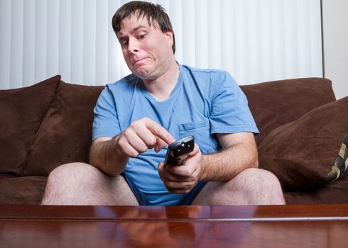 Obese male about to push a button on his remote with a look of hesitation on his face.