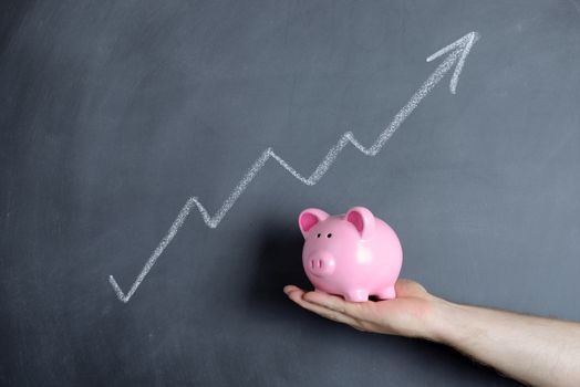 Piggy bank over chalkboard of growth chart