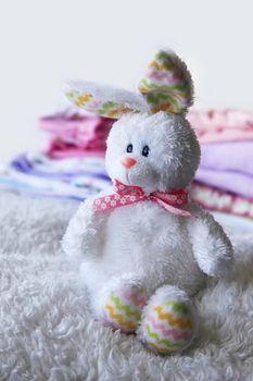 Toy on the background of the heap of children's clothing for the newborn