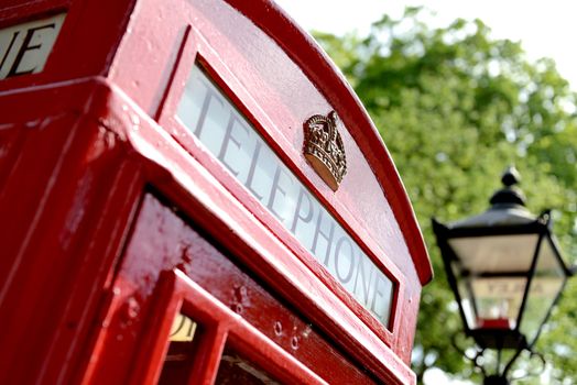 red telephone box with old fashioned london street light in soft focus