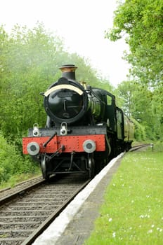 british steam train arriving at a rural platform