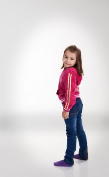 little girl in blue jeans and a red jacket posing standing in the studio