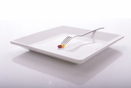 Dieting or vitamin pill for dinner on a plate