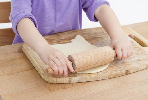 child making fresh pizza beginning with rolling out the dough