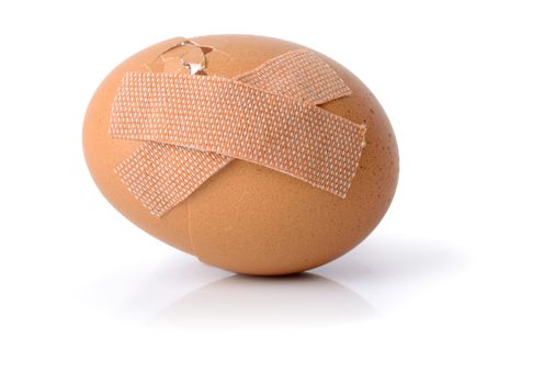 Concept of repairing a bad start, an egg with plasters isolated on a white background