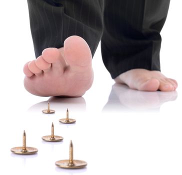 concept of unforseen problem or danger ahead, foot stepping on a pin isolated on a white background