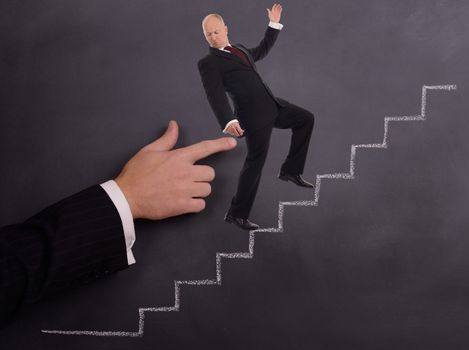 a businessman being pushed poked up stairs on a chalkboard background