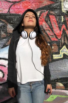 A young woman leaning on a wall and enjoying the sunlight.