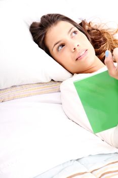 A young latin woman reading a book in bed.