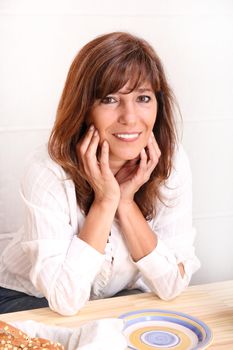 Portrait of a beautiful mature woman sitting in the kitchen.