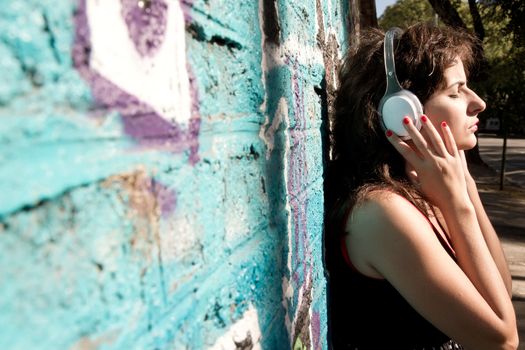 A vintage dressed girl listing to music in a urban environment.