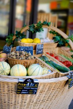 fresh fuit and vegetables in a large wovern basket in front of a small shop in france