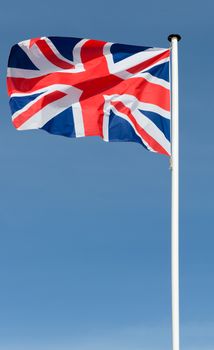 union jack bristish flag flying in a blue sky backdrop