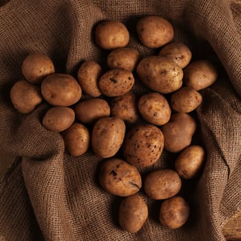 Rustic fresh unpeeled potatoes on a wooden desks