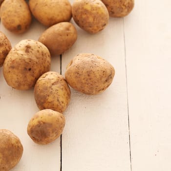 Rustic fresh unpeeled potatoes on a white wooden table