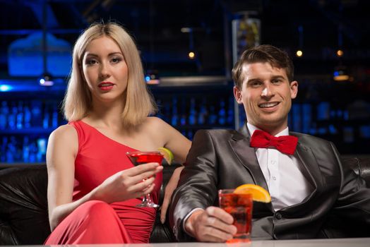 couple in a nightclub on the couch with a drink, have fun