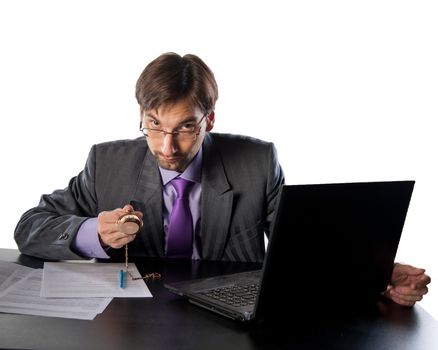 businessman in glasses behind a desk in an office with a clock in his hands