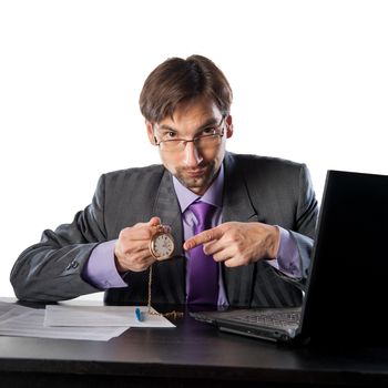 businessman in glasses behind a desk in an office with a clock in his hands