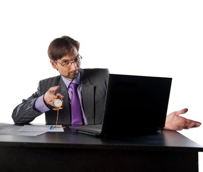 businessman in glasses behind a desk in an office with a clock in his hands