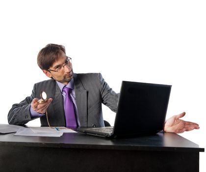 businessman in glasses behind a desk in an office with a clock in his hands